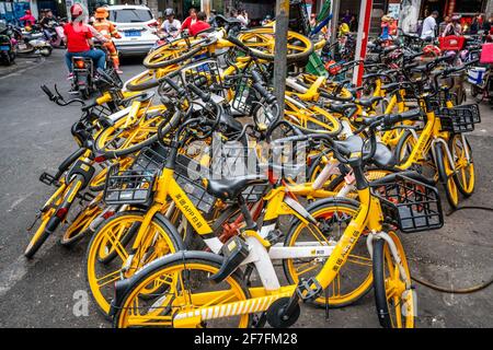 Haikou Chine , 21 mars 2021 : pile de vélo jaune partagé de Meituan Location de vélo au milieu d'une rue animée dans Haikou Hainan Chine Banque D'Images