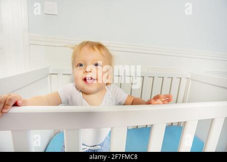 Bébé garçon debout dans le berceau avec l'expression heureuse Banque D'Images