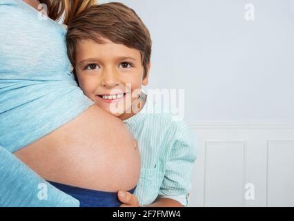 Un fils heureux embrasse le ventre enceinte de sa mère en photo Banque D'Images