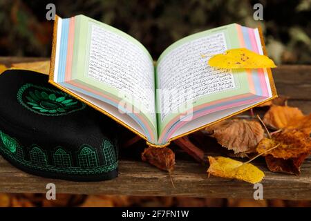 Un Saint Coran ouvert sur un stand en bois et un kufi, France, Europe Banque D'Images