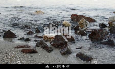 gros plan de petites vagues sur des rochers sur le blanc plage de sable Banque D'Images