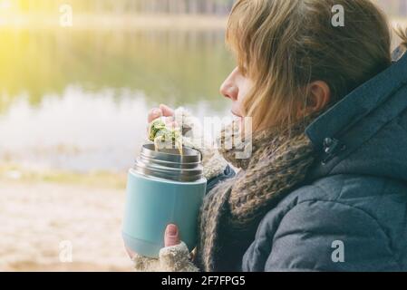 La femme mange un repas chaud à partir d'un thermos. Le concept de manger de la nourriture à l'extérieur et d'avoir un pique-nique Banque D'Images