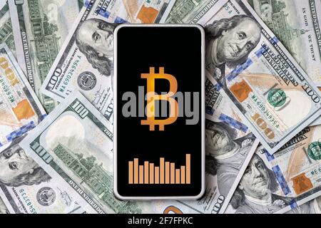 concept de gagner de l'argent sur la crypto-monnaie. Un smartphone avec un logo bitcoin et un tableau des taux de change sur l'écran du smartphone contre le b Banque D'Images