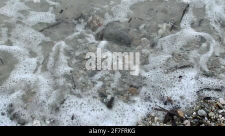 gros plan de petites vagues sur des rochers sur le blanc plage de sable Banque D'Images