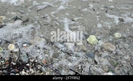 gros plan de petites vagues sur des rochers sur le blanc plage de sable Banque D'Images