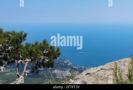 Vue de dessus de la montagne à la mer et la ville en dessous. Sur la gauche sur la montagne est un pin avec des rubans attachés pour faire un souhait. Banque D'Images