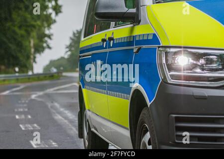 Vue partielle sur une voiture de police allemande. Phares allumés et lettres de police sur la carrosserie depuis le côté passager. Fond bleu et couleur jaune Banque D'Images