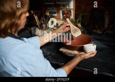 Femme artiste en céramique peignant de la poterie en atelier Banque D'Images