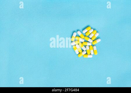 Comprimés blancs et jaunes ensemble plat pour le contenu de la médecine avec espace de copie sur fond bleu. Vue de dessus des suppléments vitaminiques. Concept médical. Banque D'Images
