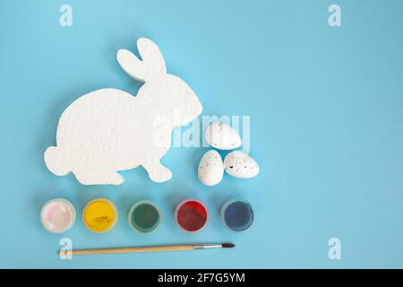 Figurine blanche de lapin ou de lapin pour décorer, peindre et brushe sur fond rouge. Pâques bricolage avec les enfants. Vue de dessus avec espace de copie. Banque D'Images