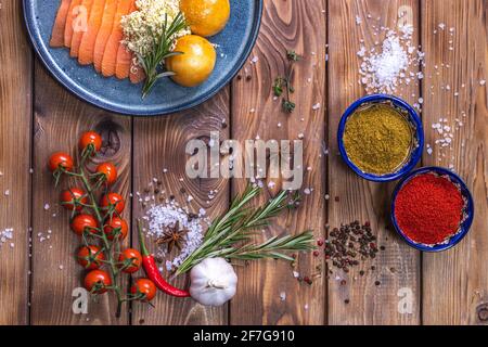 Tranches de truite sur une assiette, petits pains frais, orange, piment, tomates cerises, romarin sur fond de bois brun. Le concept de service de restaurant. Banque D'Images