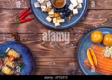 Tranches de truite sur une assiette, petits pains frais, orange, piment, tomates cerises, raisins avec fromage sur fond de bois brun. Le concept de restauran Banque D'Images