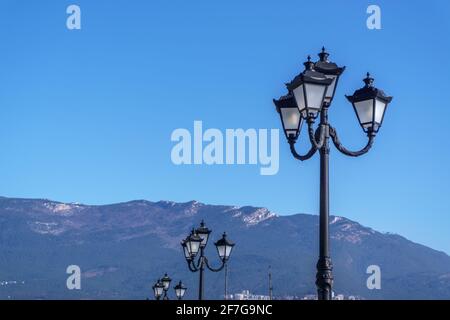 Une rangée de lumières de rue contre le ciel bleu et les montagnes. Banque D'Images