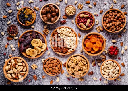 Divers fruits secs et noix dans des bols en bois, vue du dessus. Banque D'Images