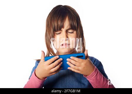 Jeune fille caucasienne avec un téléphone dans ses mains et le regardant avec chaque dégoût et reproche. Concept: Parent, éducation de la petite enfance, petite enfance Banque D'Images