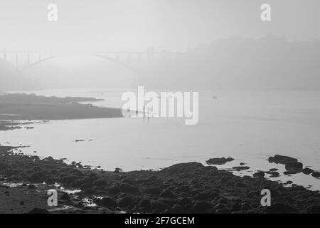 Fleuve Douro près de l'embouchure dans un matin brumeux, Porto, Portugal. Noir et blanc converti. Banque D'Images