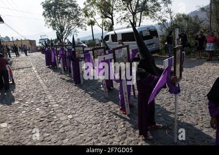 Les pénitents à capuche portent des croix lors de la procession Semana Santa à Antigua, Guatemala, une tradition solennelle de Carême reflétant la passion du Christ. Banque D'Images