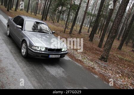 Chernigov, Ukraine - 6 janvier 2021: Ancienne voiture BMW série 7 (E38) sur la route dans la forêt. Temps sombre Banque D'Images