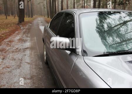 Chernigov, Ukraine - 6 janvier 2021: Ancienne voiture BMW série 7 (E38) sur la route dans la forêt. Temps sombre Banque D'Images