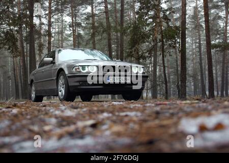 Chernigov, Ukraine - 6 janvier 2021: Ancienne voiture BMW série 7 (E38) sur la route dans la forêt. Temps sombre Banque D'Images