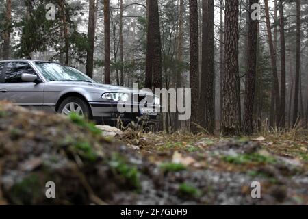 Chernigov, Ukraine - 6 janvier 2021: Ancienne voiture BMW série 7 (E38) sur la route dans la forêt. Temps sombre Banque D'Images