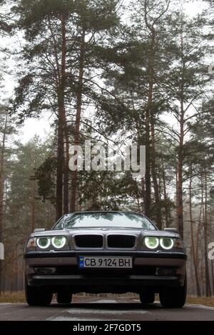 Chernigov, Ukraine - 6 janvier 2021: Ancienne voiture BMW série 7 (E38) sur la route dans la forêt. Temps sombre Banque D'Images