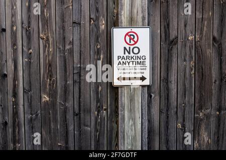 Un panneau vertical et rectangulaire en forme de no parking Anytime est placé sur une clôture en bois abîmé à London, Ontario, Canada, février 2021. Banque D'Images