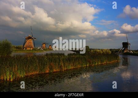 romantische Windmühle am Rande eines Kanals in Kinderdijk BEI dramatischer Wolkenstimmung am frühen Abend in Holland, Niederlande Banque D'Images