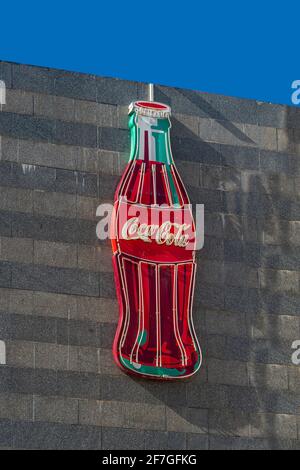 Grande bouteille de Coca-Cola au néon sur un mur. Publicité de marque. Banque D'Images