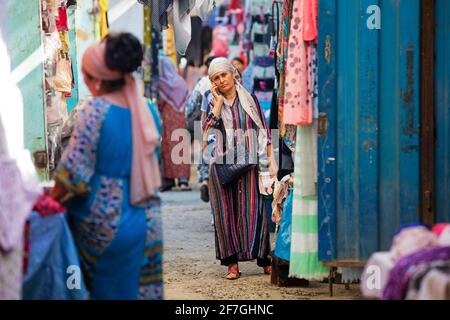 Femme kirghize avec un foulard appelant avec un smartphone sur le marché dans la ville d'Osh, Kirghizistan Banque D'Images