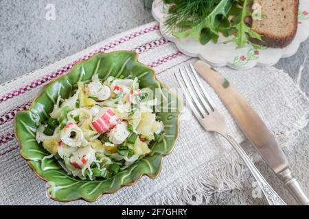 Sur la table dans une assiette de céramique salade de légumes de chou, poivre, oignons verts, bâtonnets de crabe. À côté des épices et du pain Banque D'Images