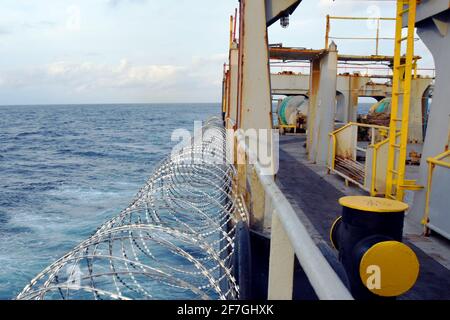 Fil barbelé ou fil de rasoir attaché à la coque, à la superstructure et aux rails du navire pour protéger l'équipage contre les attaques de piraterie passant par le golfe de Guinée en Afrique. Banque D'Images