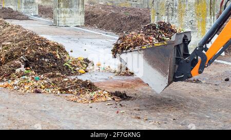 Usine de compost industriel. Terrassement travaillant avec un tas de compost dans une installation industrielle. Transformer les déchets organiques en sol de compost. Banque D'Images