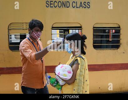 Une femme transportant un bébé est dépistée pour la température à l'arrivée en train à Dadar Terminus.les passagers arrivant dans les trains à Mumbai de l'état de Gujarat sont dépistés pour le niveau d'oxygène, la température et, s'il s'avère souffrir de fièvre, doivent subir des tests par écouvillonnage à la gare ferroviaire avant d'être autorisés à se rendre à leur destination respective. Banque D'Images