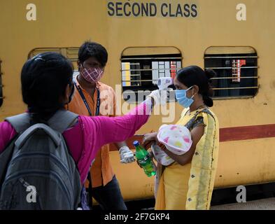 Une femme transportant un bébé est dépistée pour le niveau d'oxygène et la température à l'arrivée par train à Dadar Terminus.les passagers arrivant dans les trains à Mumbai de l'état de Gujarat sont dépistés pour le niveau d'oxygène, la température et, s'il s'avère souffrir de fièvre, doivent subir des tests par écouvillonnage à la gare ferroviaire avant d'être autorisés à se rendre à leur destination respective. Banque D'Images