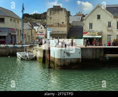 Port-en-Bessin-Huppain, France, mars 2021. Les gens se reposant dans les rues dans une petite partie de pêche en Normandie - Port-en-Bessin. Banque D'Images