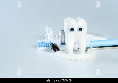 Blanche grande dent saine avec les yeux googly regarder les dents fausses. À côté de lui, il y a divers outils pour les soins dentaires. Banque D'Images