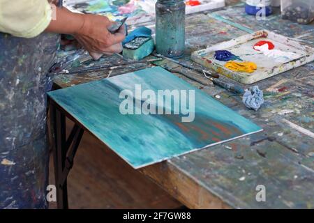 Une femme méconnaissable travaille sur un tableau. Elle utilise une flèche comme elle peint sur une toile à St Ives, Cornouailles, Angleterre Banque D'Images