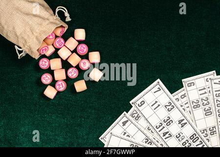 Lotto, un jeu de société familial classique. Fûts en bois en sac de jute et cartes sur une surface en velours vert. Jeu vintage, bingo. Banque D'Images