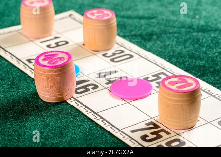 Lotto, un jeu de société familial classique. Trois fûts en bois avec chiffres, jetons rouges et bleus et carte sur la surface en velours vert pendant le match. Vintage ga Banque D'Images