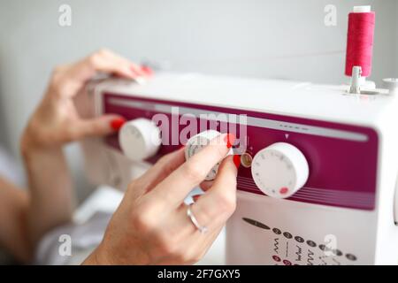 Les mains des femmes ajustent le relais sur la machine à coudre Banque D'Images