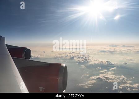 Photo de la fenêtre de l'avion. Soleil éclatant dans la fenêtre tôt le matin. Deux moteurs et nuages Banque D'Images