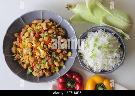 Riz blanc cuit à la vapeur servi avec du poulet, du maïs doux, du maïs pour bébés, des oignons de printemps et des poivrons. Prise de vue sur fond blanc Banque D'Images