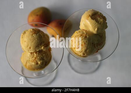 Des boules de glace à la mangue maison servies dans un verre à cocktail avec des mangues fraîches de Lalbagh. Un régal dans la chaleur estivale. Banque D'Images