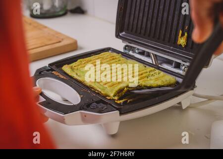 Femme préparant ou préparant une omelette d'avocat dans un grille-pain. Bonne délicieuse cuisine de style LCHF à base d'avocat, rôtie dans un grille-pain. Frais il Banque D'Images