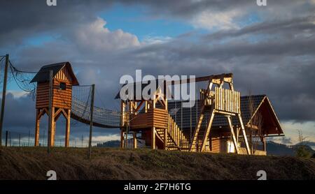 Vue sur la grenouille de l'aire de jeux en bois pour enfants. Maisons et autres objets pour les enfants à jouer avec éclairé par le soleil et toile de fond majestueuse et nuageux. Banque D'Images