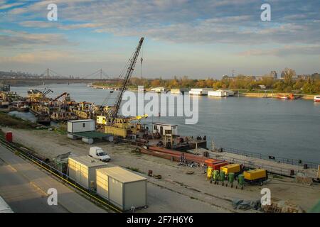 Grues, conteneurs et autres machines sur les rives de la rivière Sava dans les docklands de Belgrade en début de matinée. Le pont ADA est vu en arrière-plan. Banque D'Images