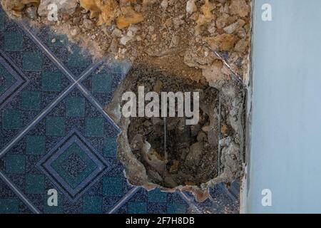 Tuyau d'eau cassé dans un appartement. Trou visible dans le sol avec des carreaux, du vieux béton et des débris. Chantier de construction tout en essayant de remédier à un le d'eau Banque D'Images