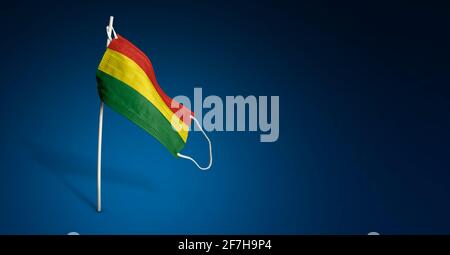 Masque de Bolivie sur fond bleu foncé. Drapeau de la Bolivie peint sur le masque médical sur le poteau. Indicateur d'attaque de virus. Concept de la bannière de la lutte ag Banque D'Images