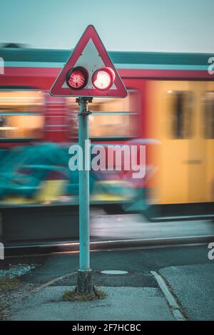 Passage à niveau de train avec feux clignotants ou clignotants pendant que le train passe. Photo nocturne d'un train dans un mouvement flou conduite au-delà de l'européen Banque D'Images